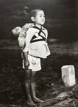 長崎の原爆で死亡した幼子を背負い焼き場に立つ少年